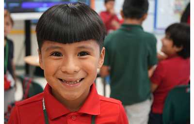 A first grade student is seen smiling the day of JA High School Heroes at Jupiter Elementary School.